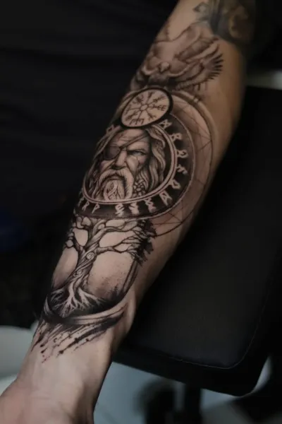 Underarmstatuering i black & grey med Oden i en runcirkel, Vegvísir och Yggdrasil, tatuerad hos Valhalla Ink i Göteborg